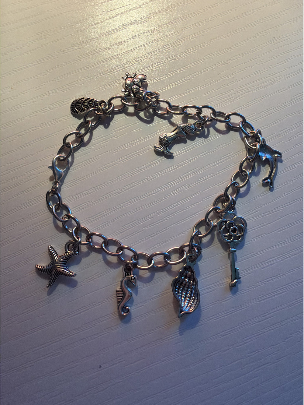 Coastal/mermaid themed charm bracelet with 8 charms.